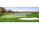 Wide shot of the lush green golf course with a sand trap and a pond with a fountain at 7201 Mission Hills Dr, Las Vegas, NV 89113