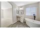 Bright bathroom featuring a sleek white soaking tub and a vanity area with mirror and black hardware at 9021 Rendon St, Las Vegas, NV 89143