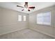 A bright carpeted bedroom with a ceiling fan and two windows covered with shades at 9021 Rendon St, Las Vegas, NV 89143