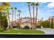 A luxurious home with a meticulously landscaped front yard, mature palm trees, and a circular driveway at 1905 Iron Ridge Dr, Las Vegas, NV 89117