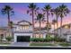 Beautiful home exterior with black garage doors, desert landscaping, and lush palm trees at 1987 Orchard Mist St, Las Vegas, NV 89135