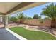 Lush backyard featuring synthetic grass, desert landscaping, patio, and privacy wall at 2555 Moonlight Valley Ave, Henderson, NV 89044