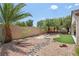 Backyard featuring artificial turf, desert landscaping, stone features, palms, and privacy wall at 2555 Moonlight Valley Ave, Henderson, NV 89044