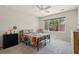 Bright bedroom with a large window overlooking palm trees, complemented by vibrant bedding and neutral carpet at 2555 Moonlight Valley Ave, Henderson, NV 89044