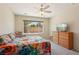 Bright bedroom features a window view, ceiling fan, and a colorful flower-patterned comforter at 2555 Moonlight Valley Ave, Henderson, NV 89044