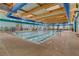 Indoor swimming pool with lane markers, a wooden ceiling, and large glass windows at 2555 Moonlight Valley Ave, Henderson, NV 89044