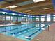 Bright indoor swimming pool with natural light, marked lanes, and adjacent seating area for relaxation at 2555 Moonlight Valley Ave, Henderson, NV 89044