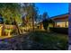 Lush backyard featuring mature trees, a grassy lawn, and ambient lighting for evening enjoyment at 33 Promontory Ridge Dr, Las Vegas, NV 89135