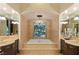 The large main bath features dual sinks, soaking tub, chandelier, and beautiful travertine tile at 33 Promontory Ridge Dr, Las Vegas, NV 89135