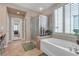 Bright bathroom featuring a soaking tub, glass enclosed shower, tile flooring and a view into the bedroom at 4408 Oasis Plains Ave, North Las Vegas, NV 89085