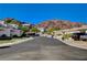 A quiet street showcases well-kept homes set against a mountain backdrop and lush green trees at 483 Marina Cv, Boulder City, NV 89005