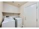 A functional laundry room with a washer, dryer, and storage shelf at 5817 Pirate Ship Dr, North Las Vegas, NV 89031