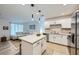 Open-concept kitchen with white cabinets, stainless steel appliances, island, and view into the cozy living room at 709 Pickled Pepper Pl, Henderson, NV 89011