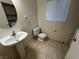 Cozy half bathroom featuring tile floors, pedestal sink, and a window at 8704 Autumn Wreath Ave, Las Vegas, NV 89129