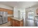 Bright kitchen features wood cabinets, stainless steel refrigerator, and an island overlooking the backyard pool at 9421 Wisdom Valley Ave, Las Vegas, NV 89149