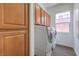 Well-lit laundry room with wood cabinets above front load washer and dryer at 9421 Wisdom Valley Ave, Las Vegas, NV 89149