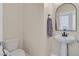 Half-bathroom featuring a pedestal sink, a round mirror, and a white toilet at 953 Via Del Tramonto St, Henderson, NV 89011