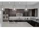 Modern kitchen with stainless steel appliances, dark cabinets, granite countertops, and stylish pendant lighting at 10181 Mount Harlow Ct, Las Vegas, NV 89141