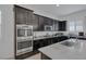 Gourmet kitchen featuring stainless steel double ovens, dark cabinetry, and a spacious island with granite countertops at 10181 Mount Harlow Ct, Las Vegas, NV 89141