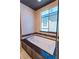 Bright bathtub featuring tiled walls, a shower head, a window, and dark granite trim at 10404 Mystic Pine Rd, Las Vegas, NV 89135