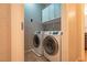 Convenient laundry room equipped with modern washer and dryer units, cabinets, and wall-mounted shelving for organization at 10404 Mystic Pine Rd, Las Vegas, NV 89135
