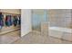 Tiled bathroom with glass shower, soaking tub, and walk-in closet at 10673 Bonchester Hill St, Las Vegas, NV 89141