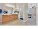 Bathroom with double sinks, wood cabinets, and adjacent bedroom at 10673 Bonchester Hill St, Las Vegas, NV 89141