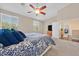 Comfortable bedroom with a ceiling fan, large windows, and a view into a living area at 10673 Bonchester Hill St, Las Vegas, NV 89141