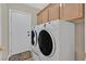 Bright laundry room featuring a modern washer and dryer set, and wood cabinets at 10673 Bonchester Hill St, Las Vegas, NV 89141