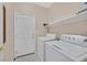 Bright laundry room features a washer, dryer, shelving, and tile flooring at 10701 Morning Harbor Ave, Las Vegas, NV 89129