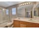 Bright bathroom with a double sink vanity, large mirror, and a shower over tub with glass doors at 10804 Mason Hill Ave, Las Vegas, NV 89166