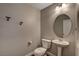 Cozy half bathroom with modern fixtures, a pedestal sink, and a round mirror for a clean look at 10804 Mason Hill Ave, Las Vegas, NV 89166
