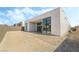 Modern home's exterior with black-framed windows, a covered patio, and dirt landscaping on an expansive lot at 10919 Vista Altura Ave, Las Vegas, NV 89135