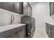 This laundry room features gray cabinetry, a white countertop, a modern gold faucet, and a stacked washer and dryer set at 10919 Vista Altura Ave, Las Vegas, NV 89135