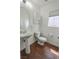 Well-lit bathroom with white fixtures, wood-look floors, and a large mirror at 1135 Paradise Mountain Trl, Henderson, NV 89002