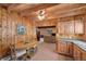 Charming kitchen with wood paneled walls, cabinets, ceiling beams, and view into the living room at 4581 Aspen Ave, Mount Charleston, NV 89124
