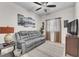 Cozy living room with a gray sofa, ceiling fan, mounted television, and a window for natural light at 4725 Blaise Ave # 103, North Las Vegas, NV 89084
