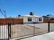 Single-story home with a white exterior, gravel yard, black fence, and wood fence in the background at 532 N 9Th St, Las Vegas, NV 89101