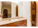 Bathroom vanity with stone countertop, wood cabinets, and large mirror reflecting archway features at 8120 W Red Coach Ave, Las Vegas, NV 89129