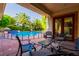 Covered patio with outdoor seating, overlooking a gated pool area and lush landscaping at 8120 W Red Coach Ave, Las Vegas, NV 89129