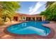 A clear blue swimming pool is bordered by a red brick patio and manicured greenery at 8120 W Red Coach Ave, Las Vegas, NV 89129