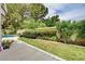 Landscaped backyard with lush green lawn, mature trees, and a sparkling pool in the distance at 8224 Horseshoe Bend Ln, Las Vegas, NV 89113