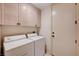 Cozy laundry room with a washer and dryer next to wooden cabinets and a white door at 8224 Horseshoe Bend Ln, Las Vegas, NV 89113