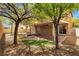 Backyard with covered patio, paver flooring, stone firepit, and mature shade trees at 9047 Harbor Wind Ave, Las Vegas, NV 89178