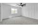 Spacious bedroom with carpet, a ceiling fan, a large window, and a modern accent wall at 9047 Harbor Wind Ave, Las Vegas, NV 89178