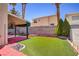 Well-maintained backyard featuring green turf, brick accents, and a covered patio at 9451 Natoma Station Pl, Las Vegas, NV 89123