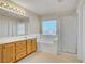 Bathroom with wood cabinets, large vanity mirror, separate tub and glass-enclosed shower at 9451 Natoma Station Pl, Las Vegas, NV 89123