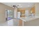 Bright eat-in kitchen with sliding glass doors to the backyard, tile floors, wooden cabinetry and white appliances at 9451 Natoma Station Pl, Las Vegas, NV 89123