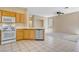 Bright kitchen with wooden cabinets, white appliances, and tile flooring overlooking an adjacent living room at 9451 Natoma Station Pl, Las Vegas, NV 89123
