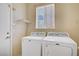 Dedicated laundry area with tile flooring, two machines, a small shelf, and a window for natural light at 9451 Natoma Station Pl, Las Vegas, NV 89123